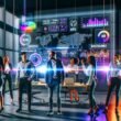 Team junger Marketing-Spezialisten betrachtet ein großes digitales Dashboard mit farbenfrohen KPI-Grafiken, digitalen PR-Analysen und Echtzeitdaten in einem modernen Büro voller Technologie und Tageslicht.