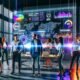 Team junger Marketing-Spezialisten betrachtet ein großes digitales Dashboard mit farbenfrohen KPI-Grafiken, digitalen PR-Analysen und Echtzeitdaten in einem modernen Büro voller Technologie und Tageslicht.