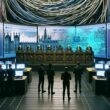 Futuristischer Serverraum mit Adern-ähnlichen Kabelbäumen, Bundestagspult, digitalen Gesetzestexten und Gruppen aus Entwicklern und Politikern vor interaktiven Bildschirmen mit GitHub-Daten.