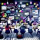Kreatives Team im modernen Großraumbüro brainstormt an digitaler Tafel mit Post-its, Datencharts und Laptops für eine datengetriebene PR-Kampagne.