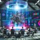 Professionals aus Wirtschaft und Technik diskutieren an einem Konferenztisch um ein holografisches 3D-Modell einer Maschine mit visualisierten Datenströmen und digitalen Anzeigen in moderner Industrielocation.