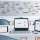 Moderner, minimalistischer Schreibtisch mit mehreren Geräten, geöffneten Blogmetriken-Dashboards und Whiteboard voller SEO-Strategien im Hintergrund.