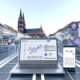 Szene aus Freiburgs Innenstadt mit Laptop, der eine SEO-Analyse zeigt, Smartphone mit lokalen Suchergebnissen und bekannten Freiburger Sehenswürdigkeiten im Hintergrund