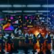 Digitales Marketing-Team arbeitet nachts an Dashboards, Funnel-Diagrammen und Conversion-Heatmaps in einem energiegeladenen, modernen Büro mit Mindmaps, Sticky Notes und UX-Playbooks.