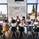 Junges, diverses SEO-Team arbeitet gemeinsam im modernen Loft-Büro in Dresden, umgeben von Laptops, Notizbüchern und Whiteboard mit SEO-Strategie-Skizzen, im Hintergrund die Dresdner Neustadt und Frauenkirche.