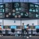 Futuristisches Großraumbüro mit digitalen Bildschirmen, holografischen API-Verbindungen und Teamarbeit zwischen Technik- und Marketingprofis