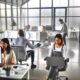 Modernes, minimalistisches Agentur-Büro mit Glaswänden und offenem Workspace, in dem ein diverses SEO-Team an Computern mit Dashboards und Code arbeitet.