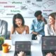 Drei junge Marketing-Profis arbeiten an Laptops in einem modernen Büro vor klaren SEO-Dashboards, tauschen Ideen zu Automatisierung und Effizienz aus und schreiben am Whiteboard.