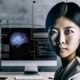 Porträt einer jungen asiatischen Frau mit intelligentem Blick in einem modernen Tech-Büro vor SEO-Dashboards und Code, umgeben von Wandgrafiken und KI-Algorithmen.