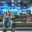 Junger Mann im Hoodie arbeitet mit Laptop und Tablet auf moderner Couch, umgeben von virtuellen Dashboards, Charts und technischen Symbolen.