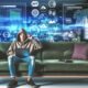 Junger Mann im Hoodie arbeitet mit Laptop und Tablet auf moderner Couch, umgeben von virtuellen Dashboards, Charts und technischen Symbolen.