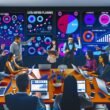 Marketingteam in einem modernen Workspace analysiert gemeinsam auf großen Bildschirmen Echtzeit-Kampagnendaten, Conversion-Funnels und wichtige Metriken auf mehreren Geräten.
