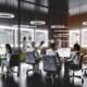 SEO-Expertenteam arbeitet in einem modernen Büro mit Glaswänden, digitalen Anzeigen für Google-Rankings und Whiteboards voller Diagramme und Notizen.