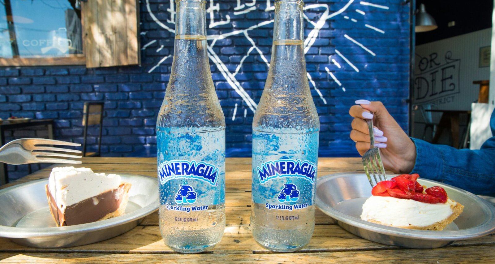 Zwei blaue und weiße Glasflaschen stehen auf einem braunen Holztisch in natürlichem Licht nebeneinander.