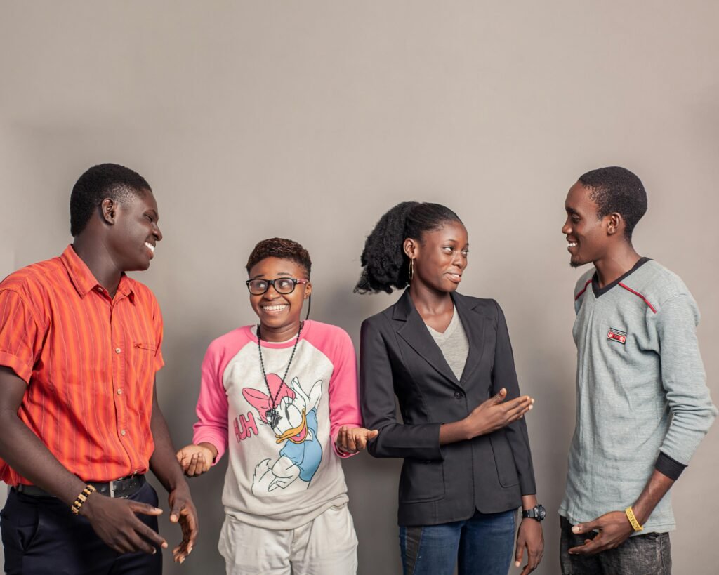 Drei Männer und zwei Frauen stehen seitlich nebeneinander vor neutralem Hintergrund, Symbol für Teamarbeit