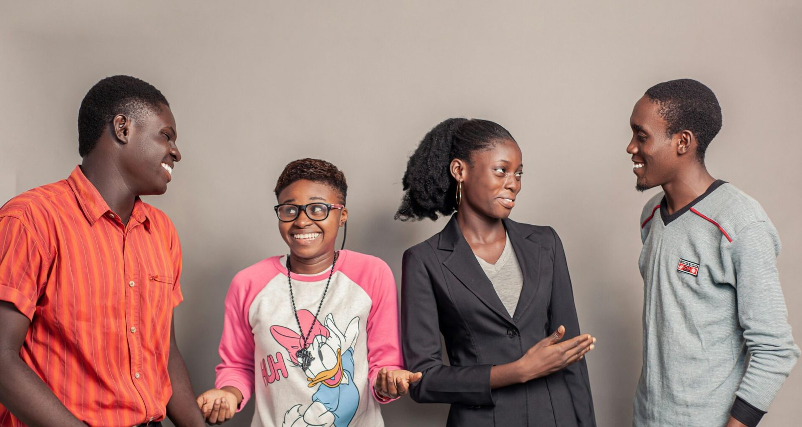 Drei Männer und zwei Frauen stehen seitlich nebeneinander vor neutralem Hintergrund, Symbol für Teamarbeit