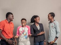 Drei Männer und zwei Frauen stehen seitlich nebeneinander vor neutralem Hintergrund, Symbol für Teamarbeit