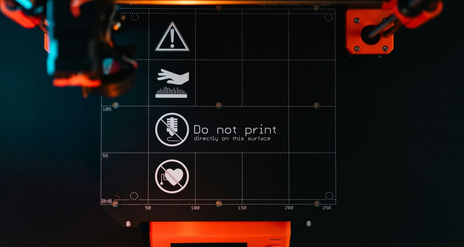 Nahaufnahme einer 3D-Drucker-Bauplattform mit klaren Warnsymbolen zur Anzeige potenzieller Gefahrenbereiche