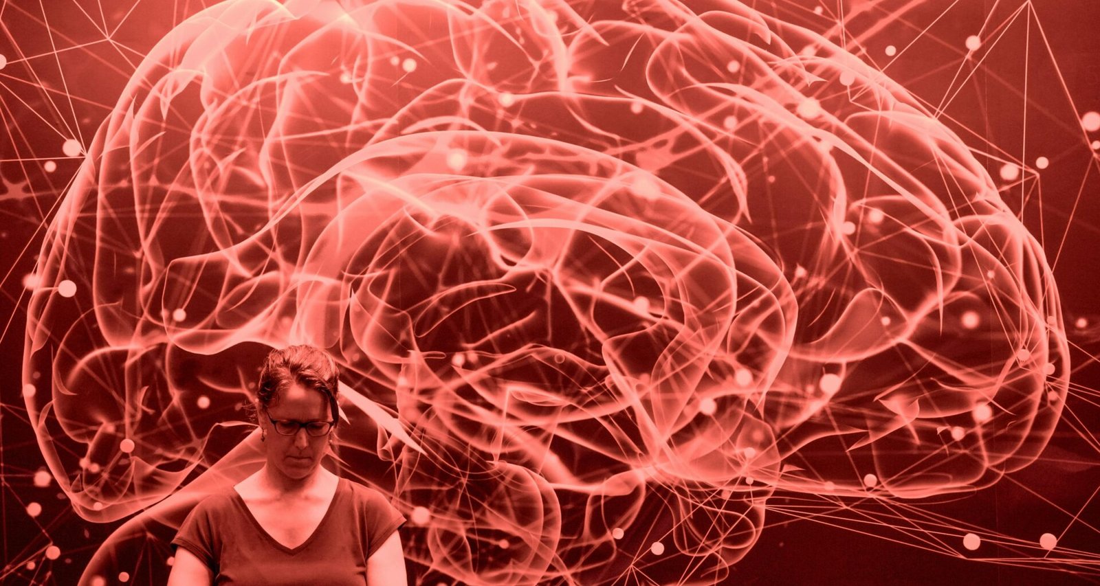 Abstraktes rotes Netzwerk in Form eines Gehirns mit einer Person im Vordergrund, Technologie visualisierend