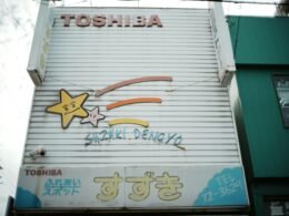 Altes Toshiba Schild mit Cartoon-Sternen und japanischen Schriftzeichen auf rostigem Metall, aufgenommen bei Tageslicht