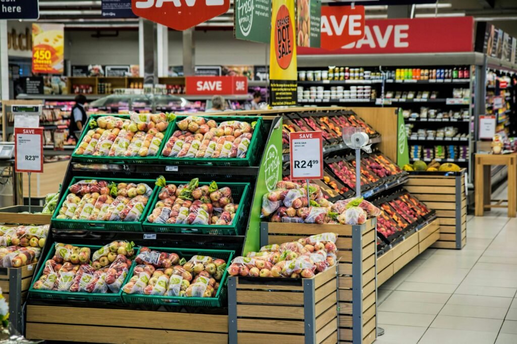 Äpfel und anderes frisches Obst werden in einer modernen Supermarktumgebung ordentlich in Kisten ausgestellt.