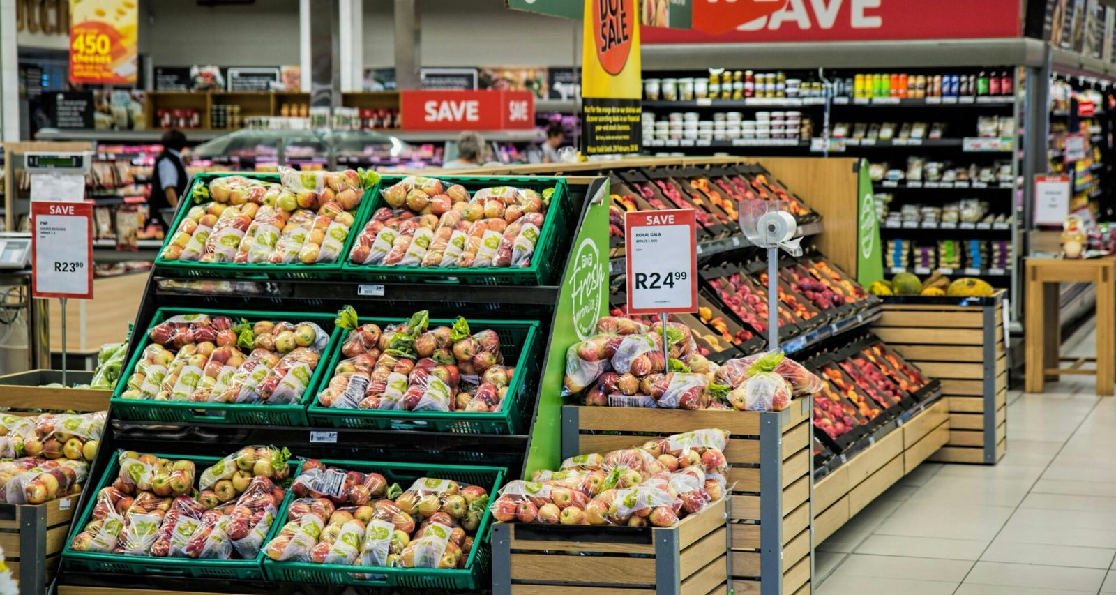Äpfel und anderes frisches Obst werden in einer modernen Supermarktumgebung ordentlich in Kisten ausgestellt.