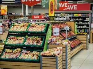 Äpfel und anderes frisches Obst werden in einer modernen Supermarktumgebung ordentlich in Kisten ausgestellt.