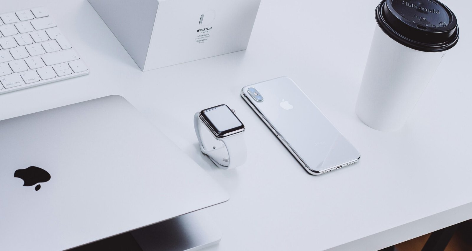 Verschiedene Apple Geräte, darunter MacBook und iPhone, ordentlich auf einem Tisch platziert