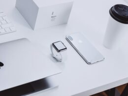 Verschiedene Apple Geräte, darunter MacBook und iPhone, ordentlich auf einem Tisch platziert