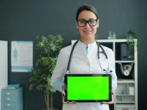 Ein Arzt hält ein Tablet mit grünem Bildschirm als Symbol für digitale Anwendungen in der Medizin.