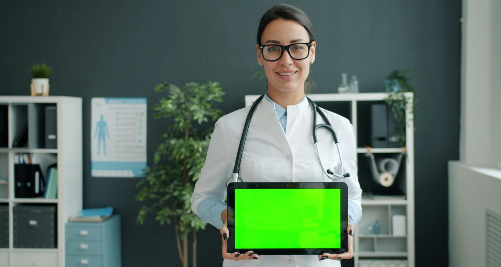 Arzt hält ein Tablet mit grünem Bildschirm, Symbol für moderne digitale Medizin und Technologien im Gesundheitswesen