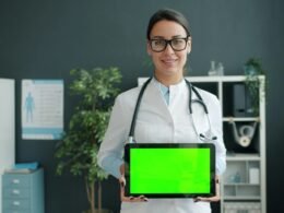 Arzt hält ein Tablet mit grünem Bildschirm, Symbol für moderne digitale Medizin und Technologien im Gesundheitswesen