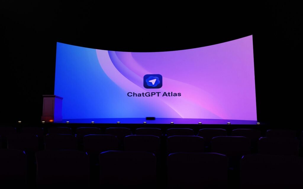 Große Leinwand mit der Aufschrift 'chatgpt atlas' in einem dunklen Raum während einer Technologiepräsentation