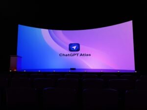Große Leinwand mit der Aufschrift 'chatgpt atlas' in einem dunklen Raum während einer Technologiepräsentation