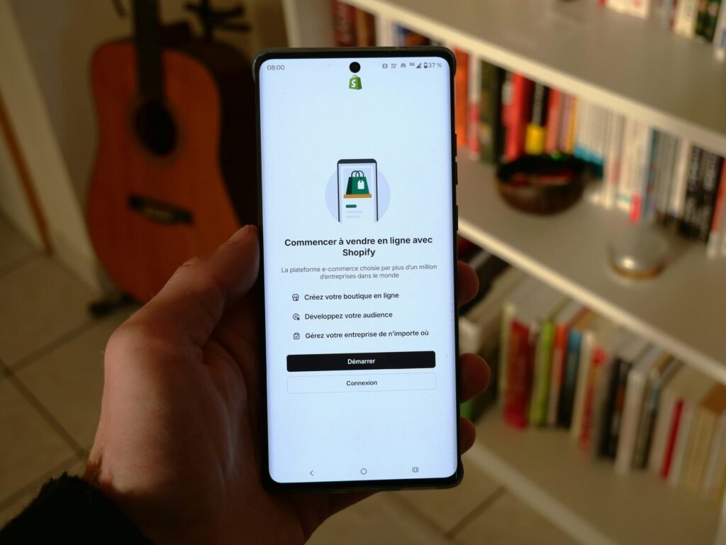 Ein Smartphone präsentiert den Einrichtungsbildschirm der Shopify App, optimal für den Start eines Onlineshops unterwegs.