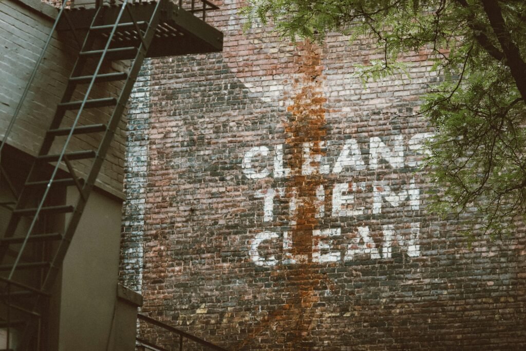 Graffiti mit dem Schriftzug ‚cleans them clean‘ auf einer Backsteinwand in urbaner Umgebung, von Jon Tyson fotografiert