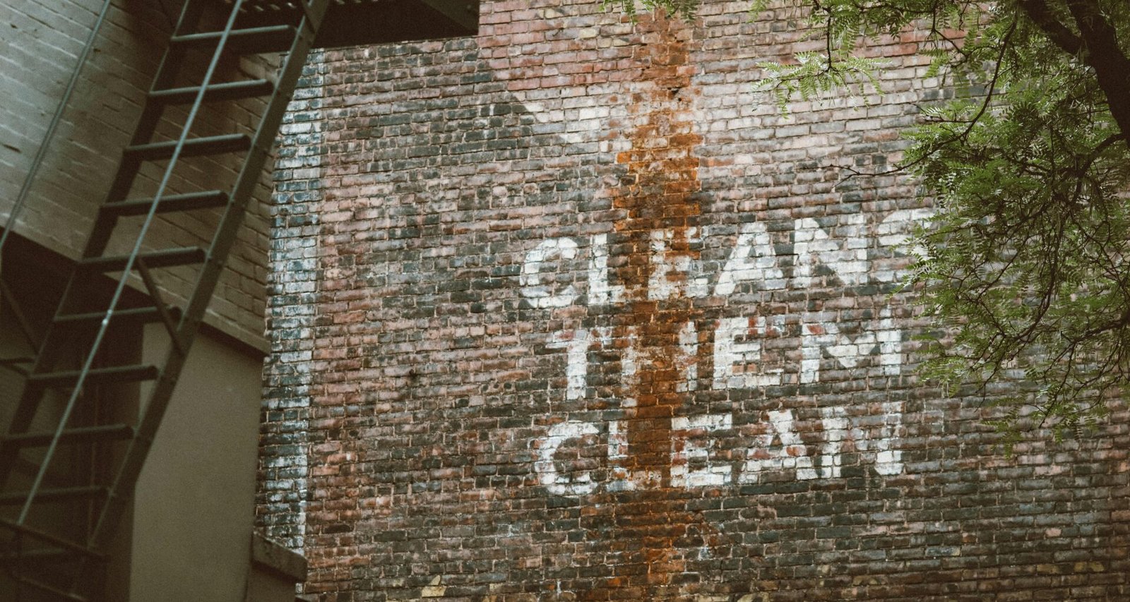 Graffiti mit dem Schriftzug ‚cleans them clean‘ auf einer Backsteinwand in urbaner Umgebung, von Jon Tyson fotografiert