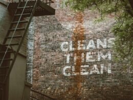 Graffiti mit dem Schriftzug ‚cleans them clean‘ auf einer Backsteinwand in urbaner Umgebung, von Jon Tyson fotografiert