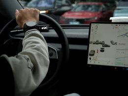 Fahrer steuert ein Auto mit großem digitalen Display im Armaturenbrett auf moderner Straße