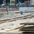 Bauarbeiten an Bahngleisen mit Schotterbett und sichtbaren Schienen auf einer offenen Baustelle