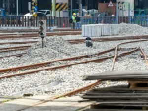 Bauarbeiten an Bahngleisen mit Schotterbett und sichtbaren Schienen auf einer offenen Baustelle