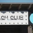 Beach Club Schild mit Wellenlogo vor blauem Himmel, modernes Design für Gastronomie, aufgenommen von Miguel A Amutio
