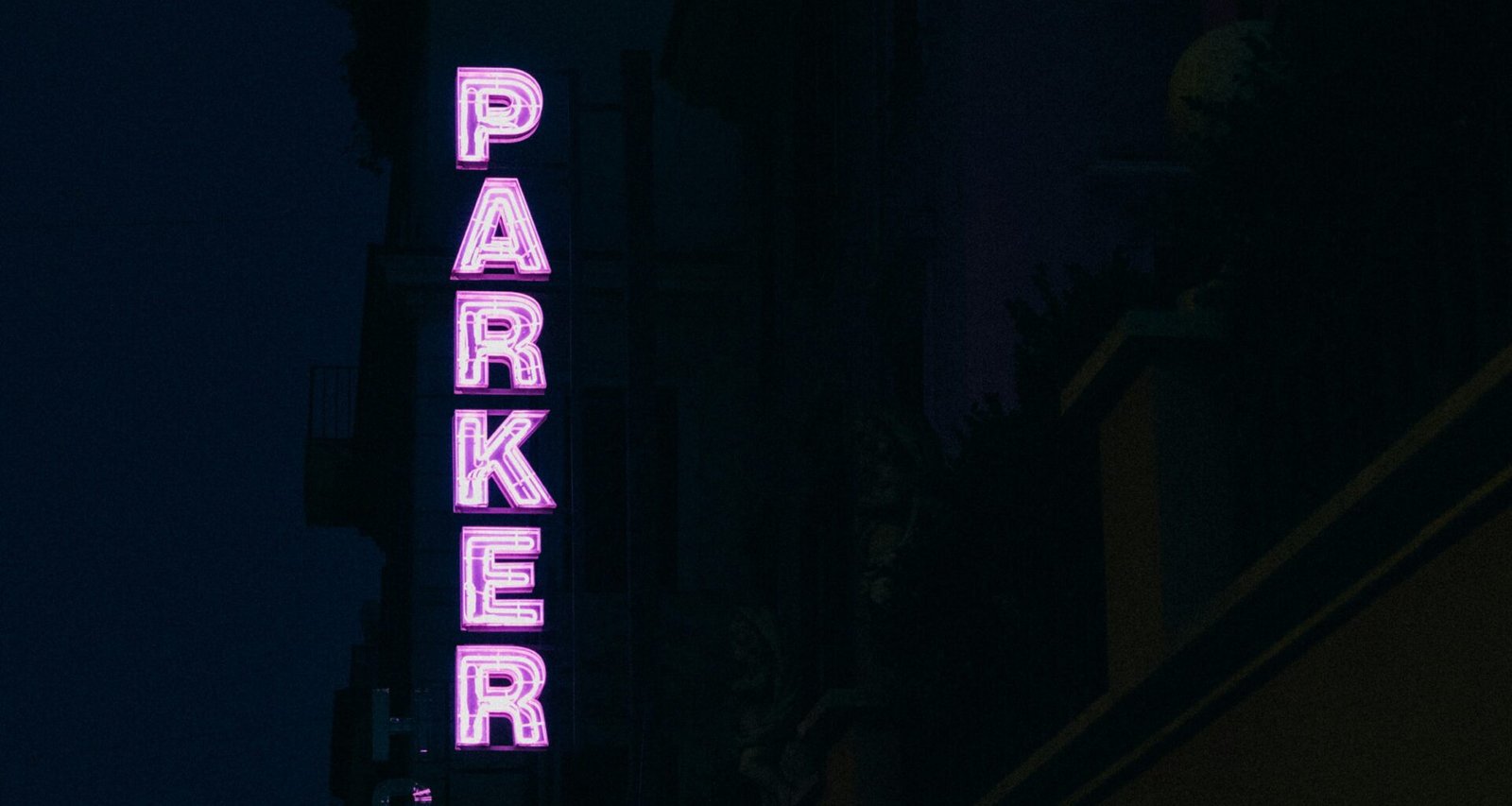 Neonschriftzug Parker leuchtet seitlich an einem Gebäude als modernes Werbeelement bei Nacht