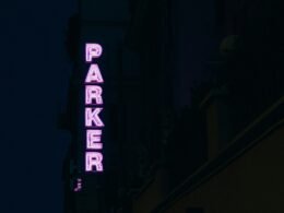 Neonschriftzug Parker leuchtet seitlich an einem Gebäude als modernes Werbeelement bei Nacht