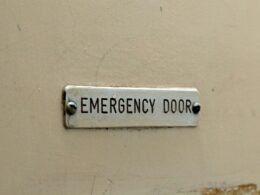 Grün beleuchtetes Notausgangs-Schild mit Richtungspfeil an einer Wand in einem öffentlichen Gebäude