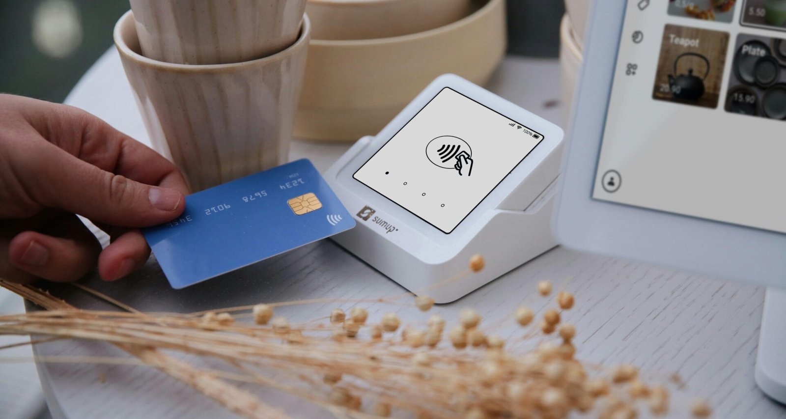 Nahaufnahme einer Hand, die mit einer Kreditkarte an einem Kartenlesegerät am Point of Sale bezahlt.