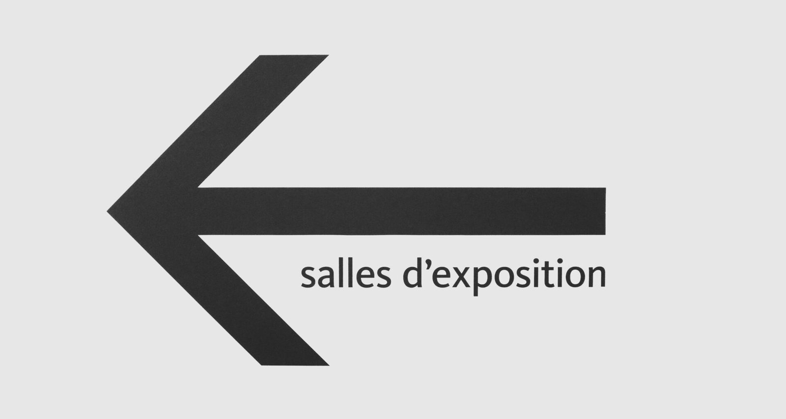 Schwarzer Schriftzug 'salles d'exposition' vor minimalistischem, hellen Hintergrund in einer modernen Ausstellung.