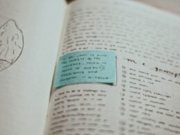 Eine blaue Karte liegt auf einem offenen Buch – Symbol für Wissenstransfer in digitalen Zeiten