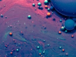 Makroaufnahme von blauen und pinken Wassertröpfchen auf einer glatten Oberfläche, Farbkontrast im Detail sichtbar