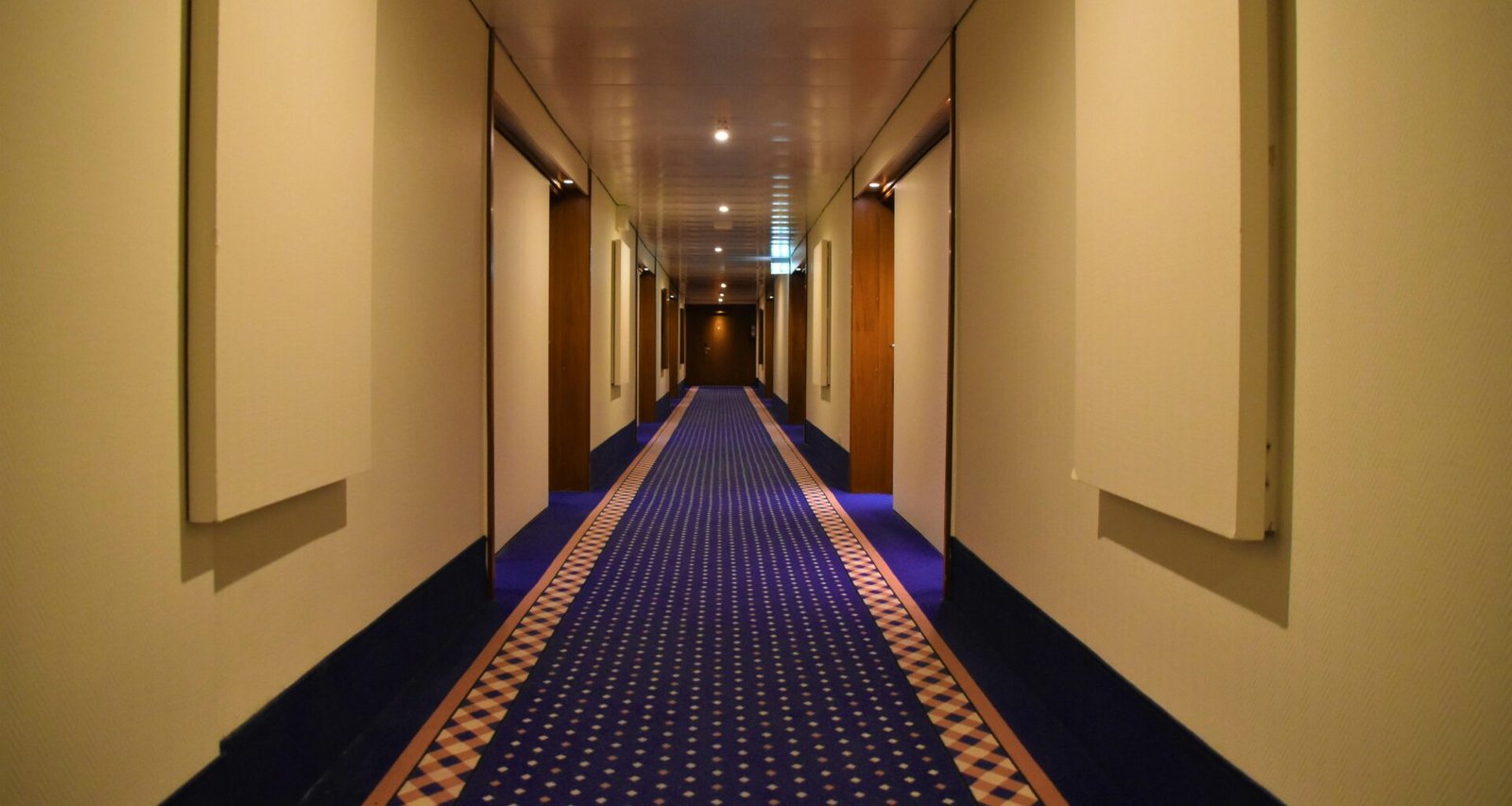 Blauer und roter Teppich verlaufen nebeneinander durch einen hellen Flur in einem modernen Gebäude